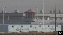 FILE - In this Dec. 3, 2018, photo, a guard tower and barbed wire fences are seen around a facility in the Kunshan Industrial Park in China's Xinjiang region. The US says it will block some Chinese cotton imports amid allegations of forced labor.