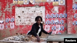 A woman prepares her stall, with election posters in the background, ahead of the presidential elections, in the suburb of Katembe, Maputo, Mozambique, Oct. 7, 2024. Voting opens across the country on Oct. 9, 2024. 