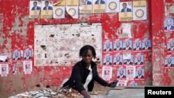 A woman prepares her stall, with election posters in the background, ahead of the presidential elections, in the suburb of Katembe, Maputo, Mozambique, Oct. 7, 2024. 