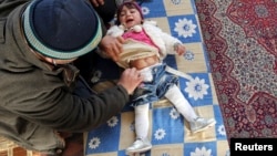 A doctor treats an internally displaced child in a school at a village outside Damascus, January 28, 2013.