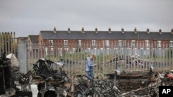 A man walks past a burnt out bus on the Shankill road in West Belfast, Northern Ireland. Authorities sought to restore calm after Protestant and Catholic youths in Belfast hurled bricks, fireworks and gasoline bombs at police and each other.&nbsp;