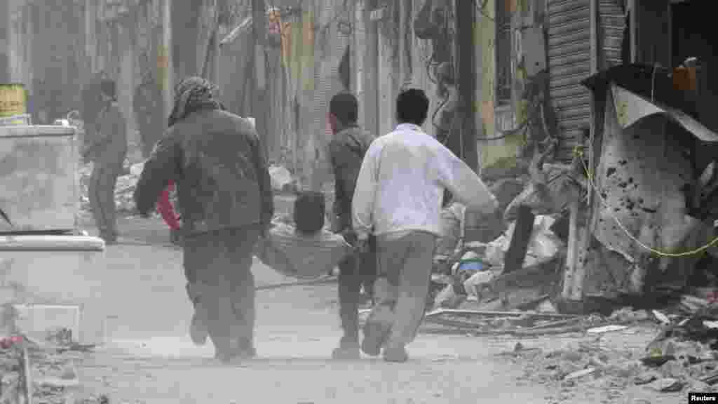 People carry a man on a stretcher after he was injured by shelling in the besieged area of Homs, Nov. 25, 2013.