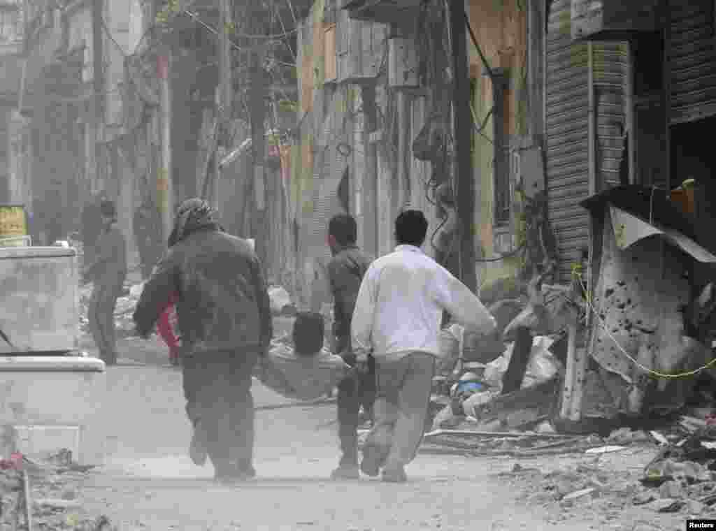 People carry a man on a stretcher after he was injured by shelling in the besieged area of Homs, Nov. 25, 2013.