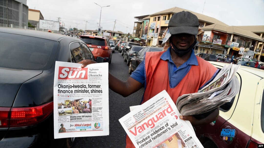 A roadside vendor holds a newspaper announcing the appointment of Ngozi Okonjo-Iweala as WTO Secretary-General in Ibadan, southwest of Nigeria, Feb. 16, 2021. 