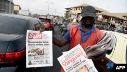 A roadside vendor holds a newspaper announcing the appointment of Ngozi Okonjo-Iweala as WTO Secretary-General in Ibadan, southwest of Nigeria, Feb. 16, 2021. 