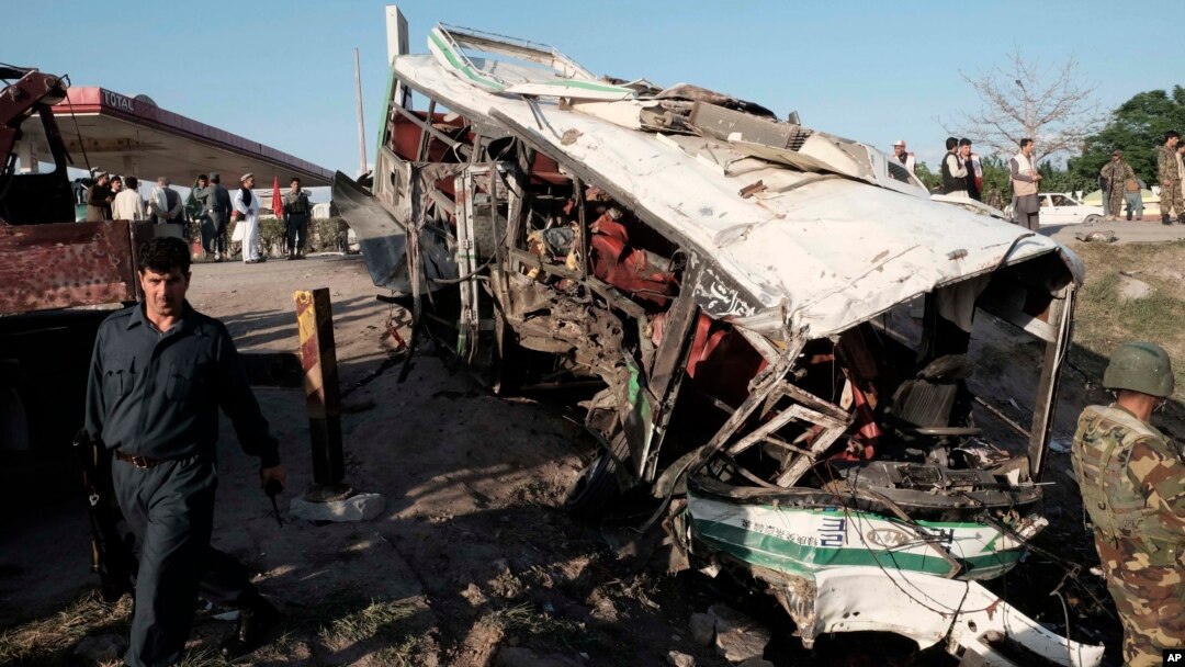 Afghans and security forces inspect damage to a bus after a suicide attack in Jalalabad east of Kabul, April 11, 2016.