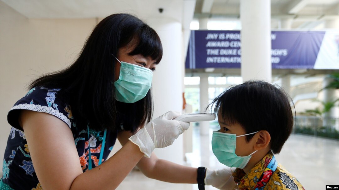 A teacher checks a student with thermal scanner at school after Indonesia confirmed its first cases of coronavirus disease (COVID-19), in Tangerang near Jakarta, Indonesia, March 6, 2020. 