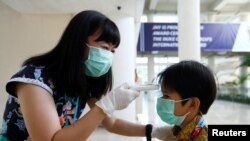 A teacher checks a student with thermal scanner at school after Indonesia confirmed its first cases of coronavirus disease (COVID-19), in Tangerang near Jakarta, Indonesia, March 6, 2020. 