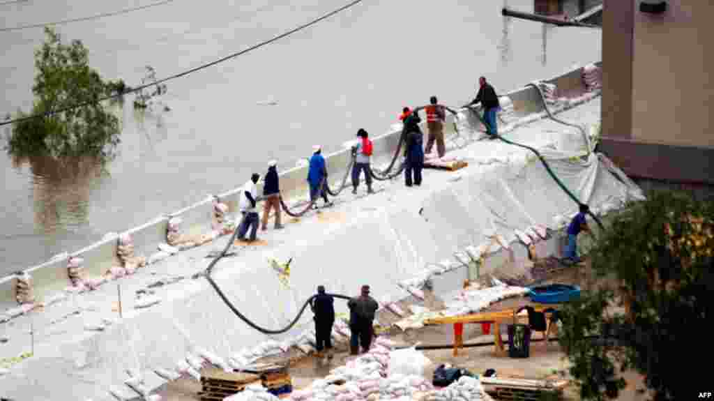 Workmen carry a drainage hose along a temporary seawall adjacent to the Ameristar Casino in Vicksburg, Miss., as river floodwaters creep up the flood walls May 14. (AP Photo/Rogelio V. Solis)