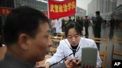 A member of the Chinese military forces gives a free medical check to a man as community service during the "Learning from Lei Feng Day" in a central square in Shanghai, March 5, 2012.