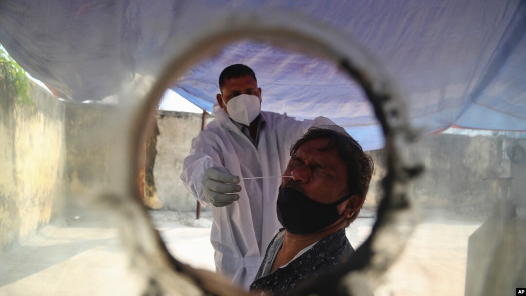 A health worker takes a nasal swab sample at a COVID-19 testing center in Hyderabad, India, Saturday, Jan. 2, 2021. India tested its COVID-19 vaccine delivery system with a nationwide trial on Saturday as it prepares to roll-out an inoculation…