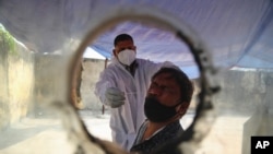 A health worker takes a nasal swab sample at a COVID-19 testing center in Hyderabad, India, Jan. 2, 2021. 