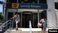 FILE - People exit a branch of the Bank of Cyprus in Nicosia, Cyprus, June 30, 2016. Russia has secured major changes to its double-tax treaty with Cyprus.
