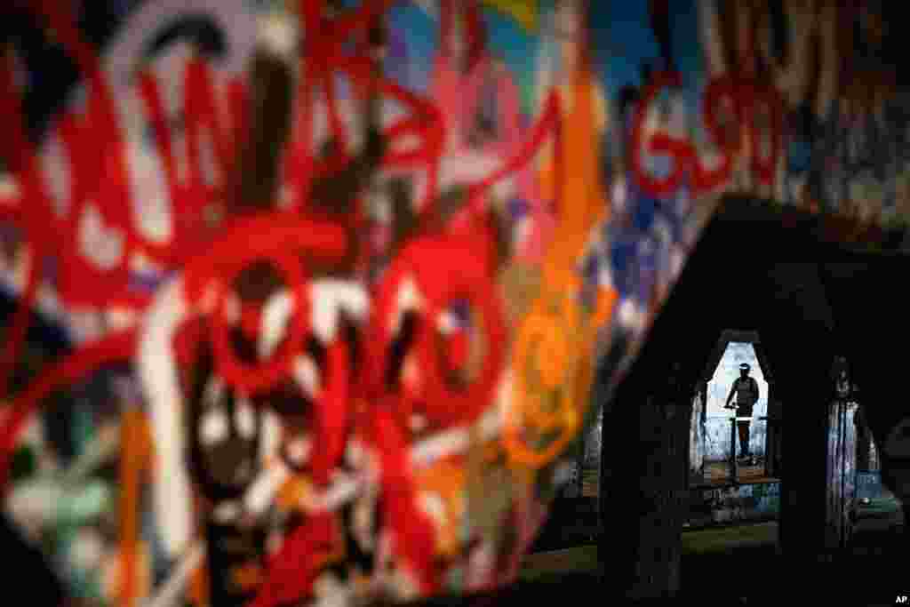 A person rides a scooter through Atlanta's Krog Street Tunnel, which runs under train tracks carrying freight cars and is known for its urban street art, Atlanta, Georgia.