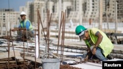 FILE - Palestinian laborers work at a construction site in Rawabi, near the West Bank city of Ramallah, Oct. 27, 2013.