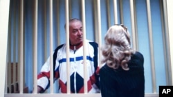 Aug. 9, 2006 file picture Sergei Skripal speaks to his lawyer from behind bars seen on a screen of a monitor outside a courtroom in Moscow