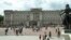FILE - People are seen in front of Britain's Queen Elizabeth II's official London residence, Buckingham Palace, in London.
