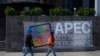 Employees walk in front of a banner at the government complex where the Asia-Pacific Economic Cooperation (APEC) Summit will take place in Lima on November 13, 2024.