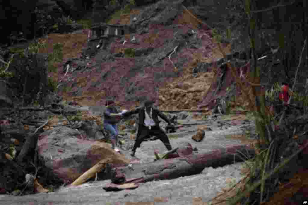 Em equilíbrio precário, residentes do bairro de Caleme, em Teresópolis, atravessando um rio cujo caudal foi engrossado pelas chuvas torrenciais desta semana.