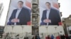 FILE - People pass posters of Serbian Prime Minister Aleksandar Vucic in Novi Sad, Serbia, March 18, 2017.