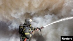 Vatrogasac gasi požar koji je izbio posle napada u Donjecku (Foto: REUTERS/Alexander Ermochenko)