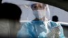 A medical staffer performs tests for COVID-19 at a drive-through at Rome's Leonardo Da Vinci airport, Friday, Oct. 9, 2020. Italy’s new confirmed caseload Friday passed 5,372, the highest levels since March. (Cecilia Fabiano/LaPresse via AP)