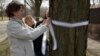 Carla Sloan (L) and Liz Ziehl, friends and neighbors of diplomat Anne Smedinghoff, who was killed in Afghanistan, tie a ribbon on a tree in River Forest, Illinois, April 8, 2013. 
