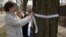 Carla Sloan (L) and Liz Ziehl, friends and neighbors of diplomat Anne Smedinghoff, who was killed in Afghanistan, tie a ribbon on a tree in River Forest, Illinois, April 8, 2013. 