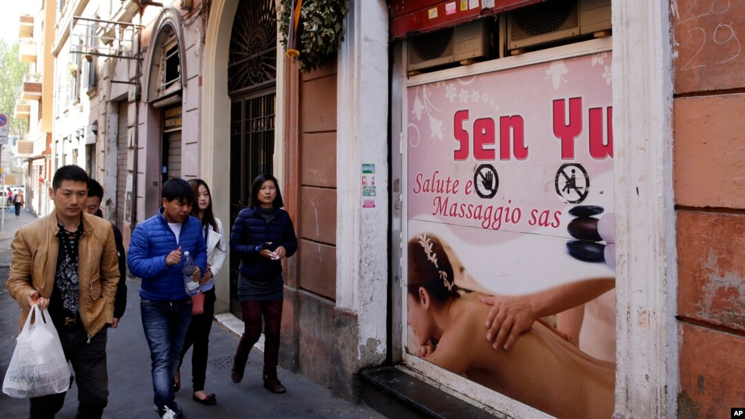 人们从位于罗马中国城的维托里奥广场的一家中国按摩中心门前经过。