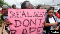 FILE - A woman carries a placard as she shouts a slogan during the "Walk Against Rape'" procession organized by Project Alert, a Lagos-based NGO focusing on women's issues, in Lagos, Nigeria, Oct. 5, 2011. 