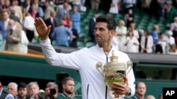 Serbia's Novak Djokovic holds the trophy after defeating Switzerland's Roger Federer in the men's singles final match of the Wimbledon Tennis Championships in London, July 14, 2019.