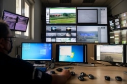 FILE - A police officer works inside the operation center at the village of Nea Vyssa near the Greek - Turkish border, Greece, May 21, 2021. An automated hi-tech surveillance network on the border aimed at deterring migrants from crossing.