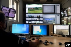 FILE - A police officer works inside the operation center at the village of Nea Vyssa near the Greek - Turkish border, Greece, May 21, 2021. An automated hi-tech surveillance network on the border aimed at deterring migrants from crossing.