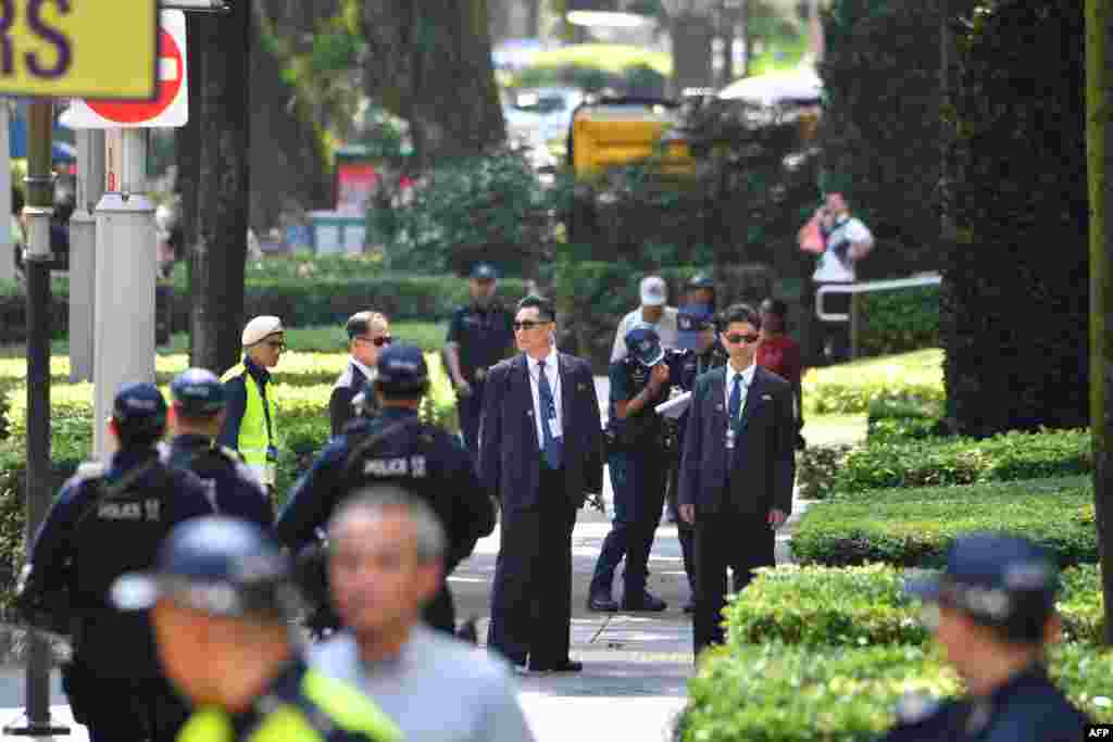 Petugas Keamanan Korea Utara (tengah, menggunakan kacamata hitam) berjaga di luar Hotel St. Regis, tempat pemimpin Korea Utara Kim Jong Un menginap, menjelang pertemuan puncak di Singapura, 11 Juni 2018. (Foto: AFP)