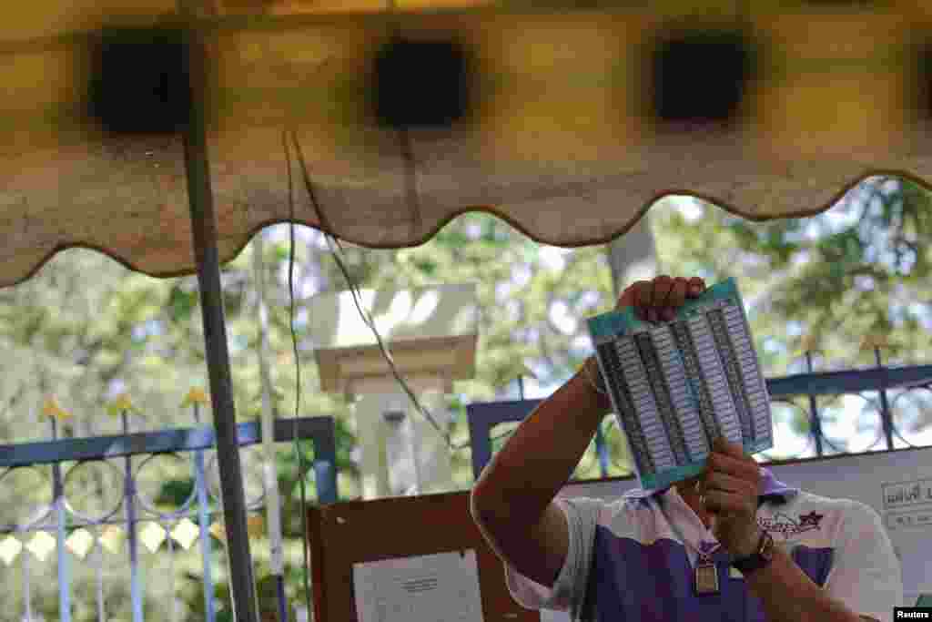 An official holds a ballot as votes are counted at a polling station in Bangkok, March 30, 2014.