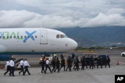 Security personnel approach a plane carrying migrants from Central Asia and India who were deported from the United States at Juan Santamaria International Airport in San Jose, Costa Rica, Feb. 20, 2025.