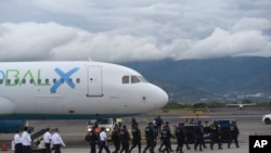 Personeli i sigurisë i afrohet një avioni me në bord emigrantë nga Azia Qendrore dhe India të cilët u dëbuan nga Shtetet e Bashkuara. Aeroporti ndërkombëtar Juan Santamaria, San Jose, Kosta Rika, 20 shkurt 2025.
