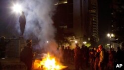 Archivo - En esta foto del 4 de julio de 2020, manifestantes se reúnen cerca de un incendio en el centro de Portland, Oregon.