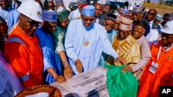 In this photo released by the Nigeria State House, Nigeria's President Muhammadu Buhari, center, looks at a plaque during the flag off of the Kolmani project ceremony in northeast, Nigeria, Nov. 22, 2022. 