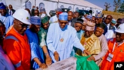 In this photo released by the Nigeria State House, Nigeria's President Muhammadu Buhari, center, looks at a plaque marking the start of drilling for oil at the Kolmani project in northeast, Nigeria, Tuesday, Nov. 22, 2022. 