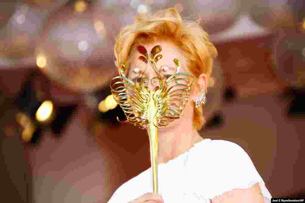 Actress Tilda Swinton holds a carnival mask as she poses for photographers upon arrival at the opening ceremony of the 77th edition of the Venice Film Festival in Venice, Italy.