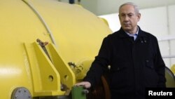 Israel's Prime Minister Benjamin Netanyahu stands next to a free-electron laser (FEL) during a visit to the Ariel University Center in the West Bank Jewish settlement of Ariel, January 8, 2013.