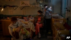 Hospital workers take care of orphaned children at the children's regional hospital maternity ward in Kherson, southern Ukraine on November 22, 2022. (AP Photo/Bernat Armangue)