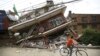 A boy riding a bicycle looks at a collapsed house after Saturday's earthquake, in Kathmandu, Nepal, April 28, 2015. 