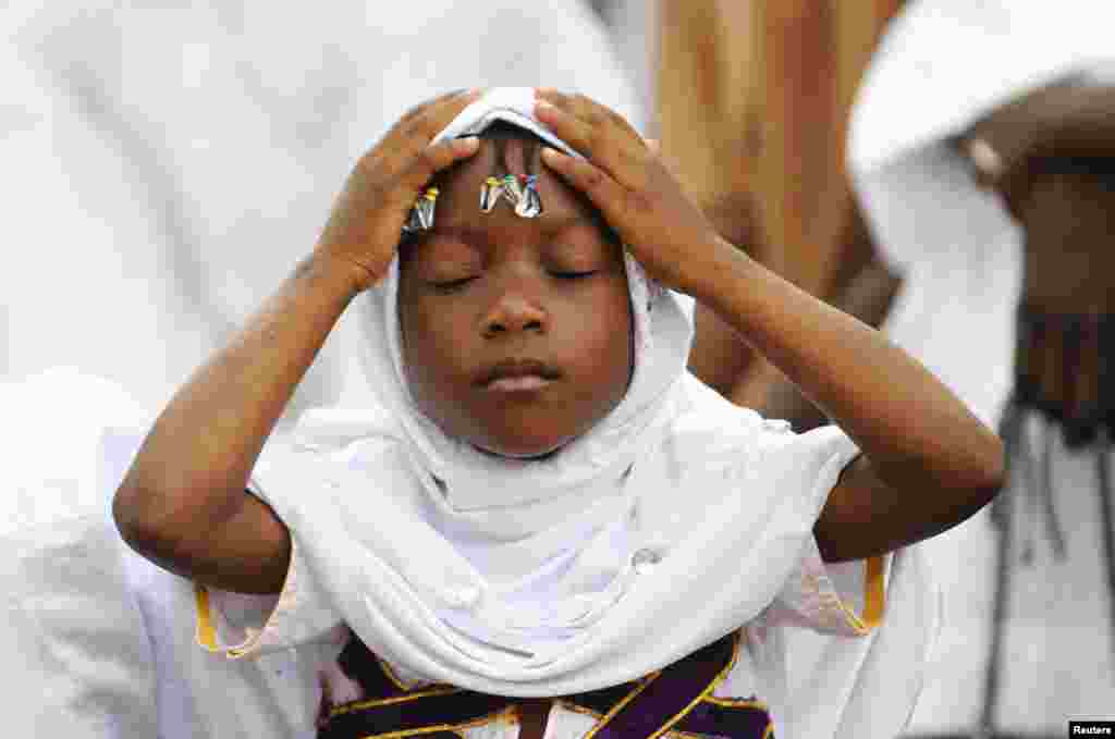 Bé gái cầu nguyện trong lễ Eid el- Kebir tại một nhà thờ Hồi giáo ở Koumassi, ở thủ đô Abidjan của Bờ Biển Ngà. Người Hồi giáo khắp thế giới mừng lễ Eid el- Kebir, còn được gọi là Eid al-Adha, bằng cách giết mổ cừu, dê, lạc đà, bò để tưởng nhớ Ðấng tiên tri Abraham sẵn sàng hy sinh con trai của mình, Ismail, theo lệnh của Thiên Chúa. 