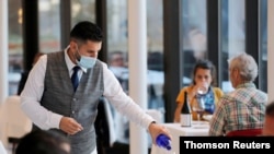 Un mesero llena un vas de agua en el restaurante Estiatorio Milos en Hudson Yards, Nueva York, el domingo 4 de octubre de 2020.