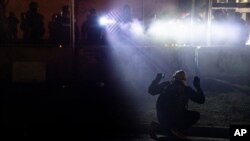 FILE - Police shine lights on a demonstrator with raised hands during a protest outside the Brooklyn Center Police Department, in Brooklyn Center, Minnesota, over the fatal shooting of African American Daunte Wright.