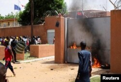 Para demonstran pro-junta yang berdemo di luar Kedubes Prancis mencoba menyalakan api sebelum dibubarkan oleh pasukan keamanan Niger, di NIamey, Minggu, 30 Juli 2023. (Foto: Souleymane Ag Anara/Reuters)