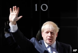 Britain's new Prime Minister Boris Johnson waves from the steps outside 10 Downing Street, London, Wednesday, July 24, 2019.