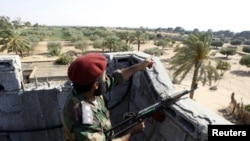 A Libyan rebel fighter points out positions of forces loyal to leader Moammar Gadhafi at Misrata's western front line, some 25 kilometres from the city center May 26, 2011